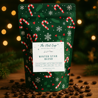 Coffee bag with Christmas design on a wooden surface with coffee beans and blurred lights in the background