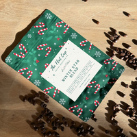 Green holiday-themed coffee bag with candy cane pattern on a wooden surface with coffee beans.