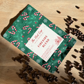 Coffee package with festive design on a wooden surface with coffee beans.